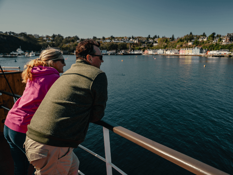Two people looking out to the clear waters and the coast line